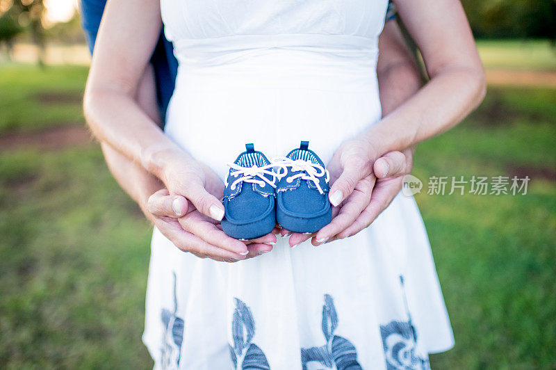 父母都抱着未出生儿子的蓝色婴儿鞋。