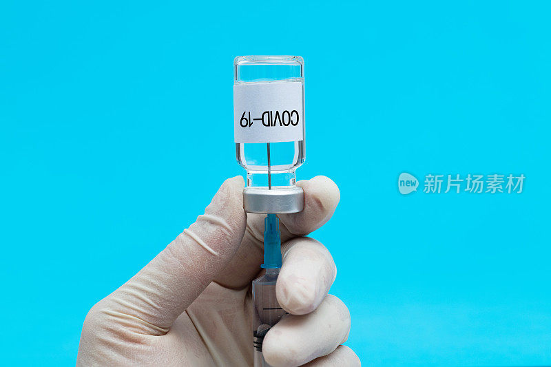 医生手持注射器和Covid-19疫苗瓶