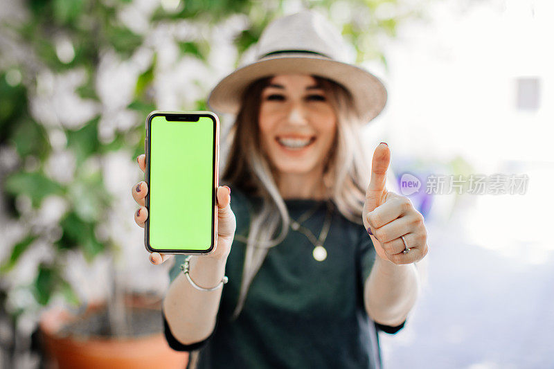 智能女人的手握和触摸手机智能手机与色度键绿色屏幕在城市背景