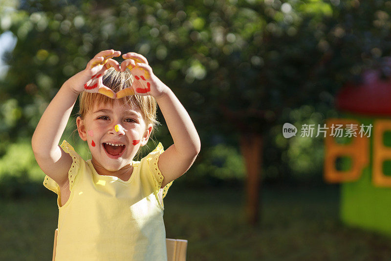 快乐的孩子用手蘸颜料画心形