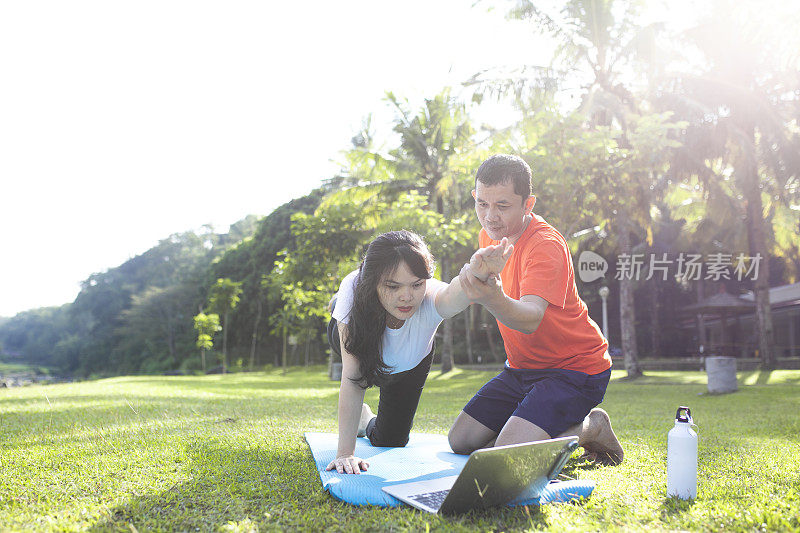 年轻的亚洲孕妇在她丈夫的帮助下做运动