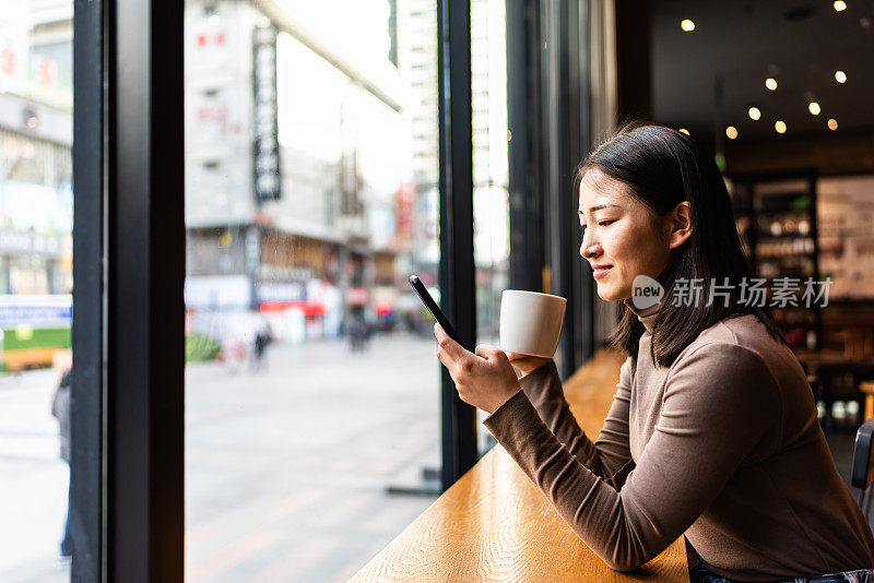 年轻的亚洲女性在咖啡店里使用智能手机