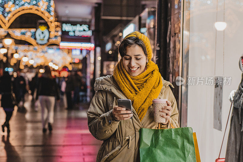 快乐的女人在节日里拿着手机购物