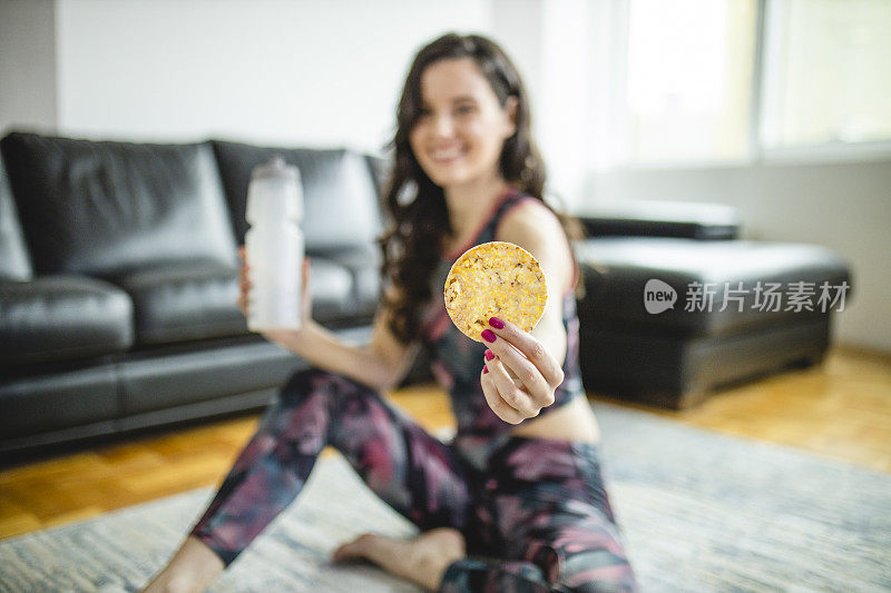 运动妇女在家锻炼后吃米饼和喝水