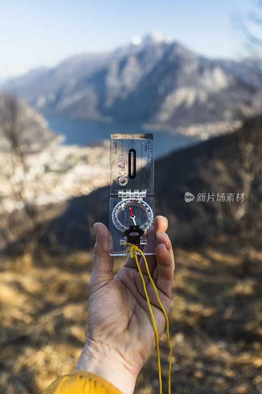 男手拿着指南针，群山在背景中，阳光灿烂