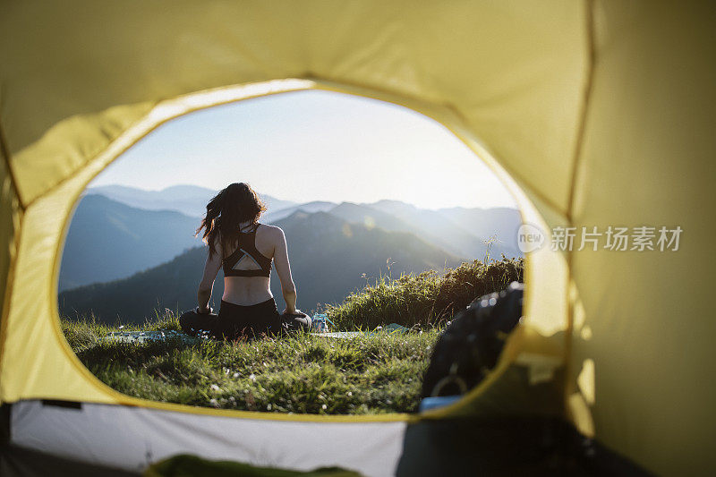 日落时分，一个年轻女子在山中的帐篷前沉思。