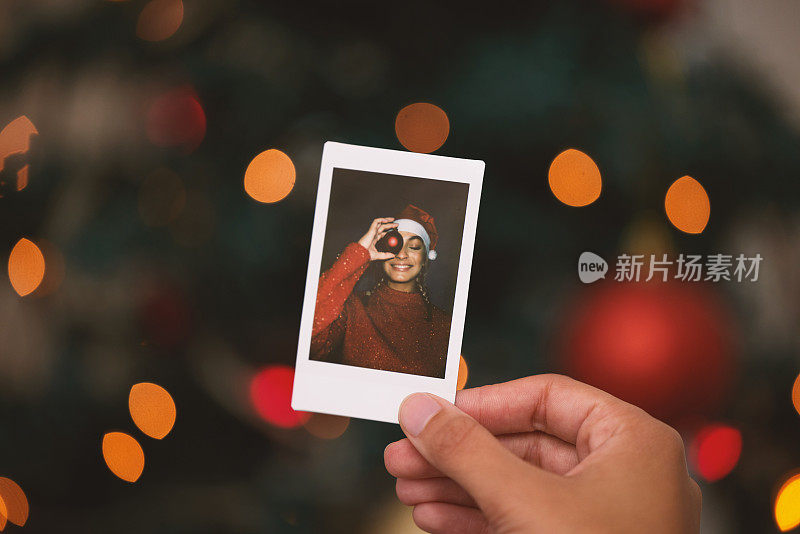 一名无法辨认的人拿着一名年轻女子庆祝圣诞节的照片