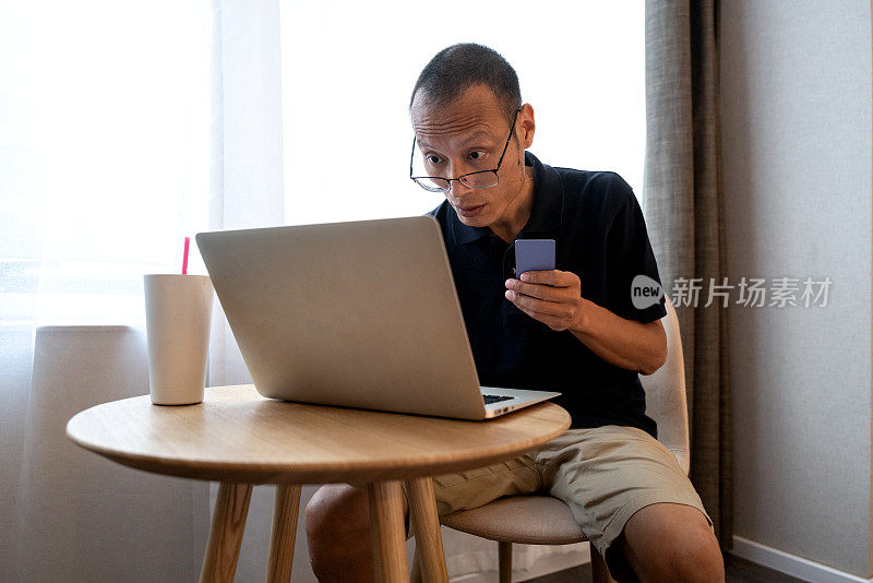 亚洲中年男子使用信用卡和笔记本电脑进行在线支付