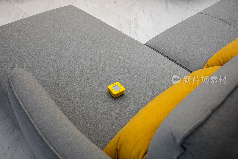 灰色沙发上黄色数码多功能闹钟的高角度拍摄