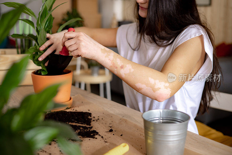 一个不知名的年轻白人妇女在家里照顾她的植物的特写