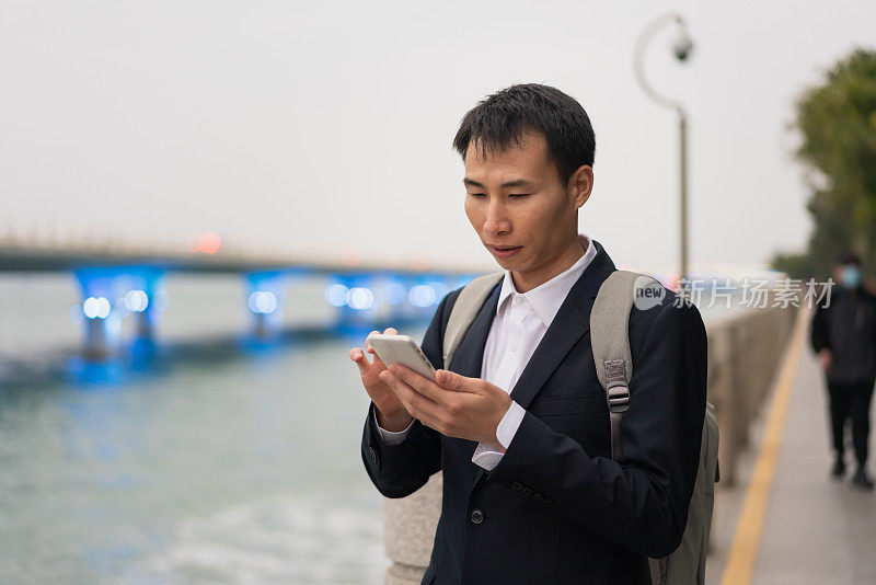 一名亚洲男子在海边使用智能手机