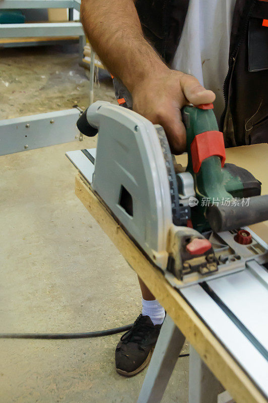 一个年轻的木匠用专业的工作工具正在用圆锯工作。