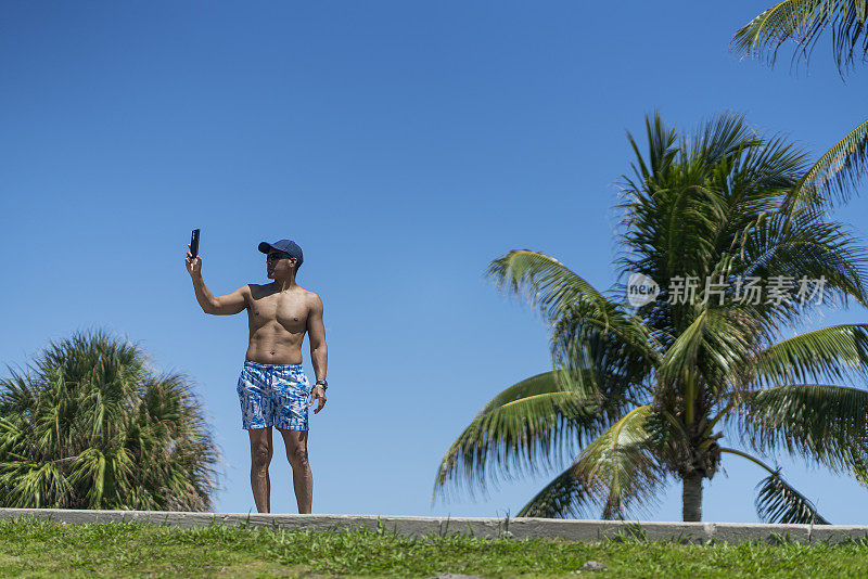 拉丁裔男子在迈阿密海滩度假，一边用手机自拍，一边享受独处的时光