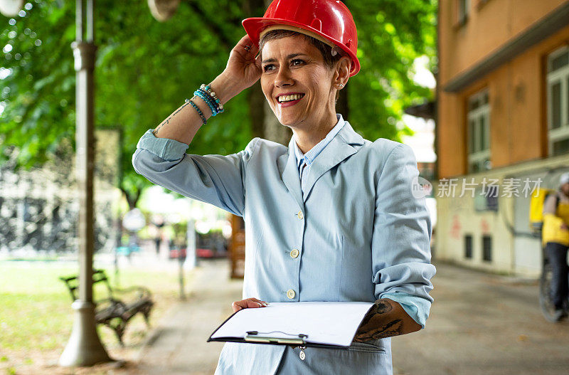 女建筑师工程师拿着文件，穿着西装，戴着安全帽