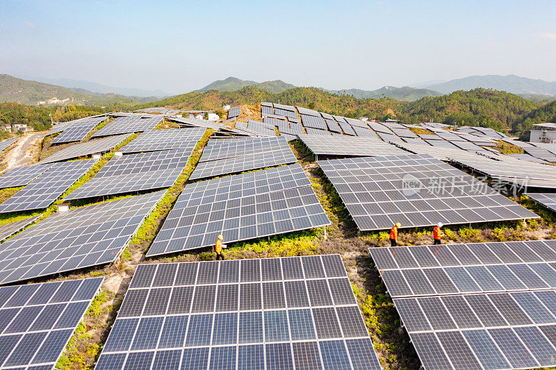 三名技术人员边走边检查太阳能电池板