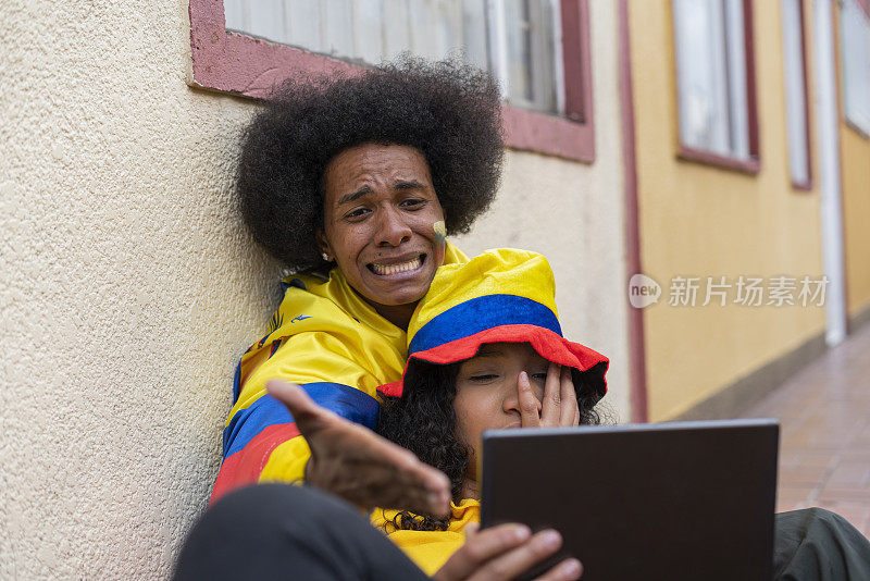 一对非洲裔拉丁夫妇在屋外用平板电脑看足球比赛