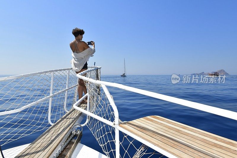 年轻女子在船上享受夏天。蓝色航行，每日乘船旅行。