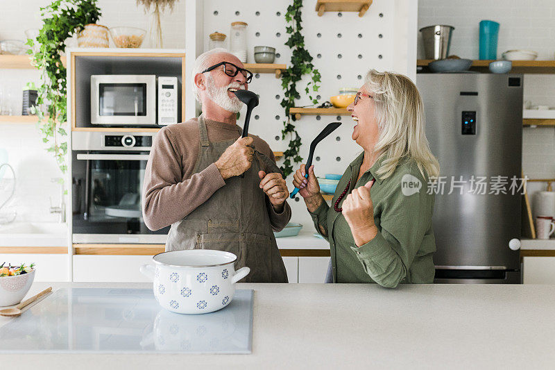 老夫妇一起在厨房做饭。退休后的生活方式，休闲和在家消磨时间。