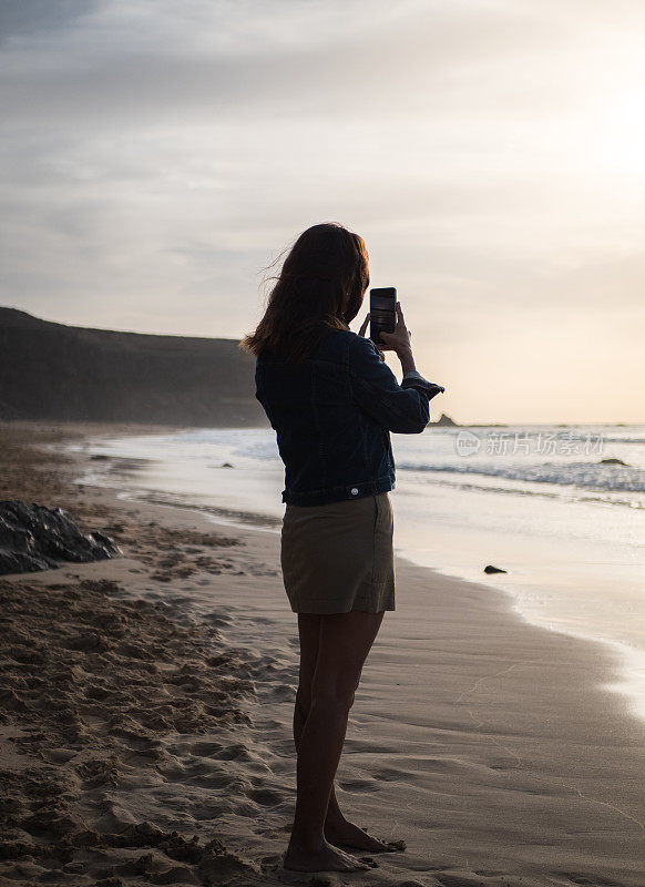 在海滩上拍摄日落的女人
