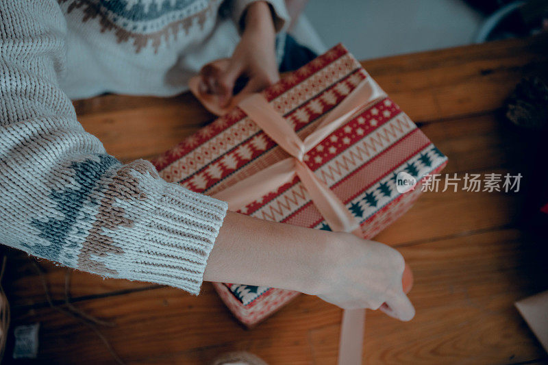 女人包装礼物，在她的礼品盒上系蝴蝶结