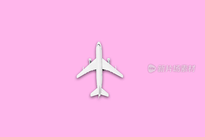 夏季旅游概念的平面设计。一架飞机的俯视图在空白的粉红色粉彩屏幕与复制空间。暑假旅行