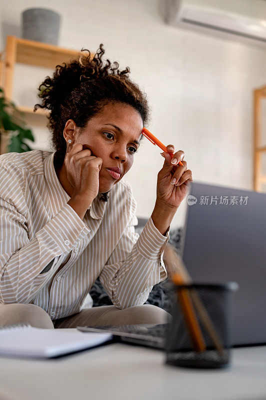 年轻的非洲裔女商人坐在笔记本电脑前计算开支