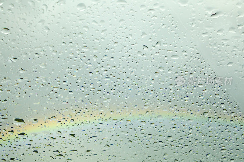 雨滴落在玻璃表面。彩虹