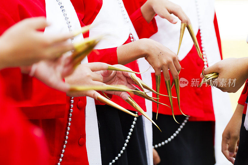 清迈省，穿着红色衣服的十几岁的泰国朗姆酒舞者伸展的手指和金色指甲延伸的手的特写