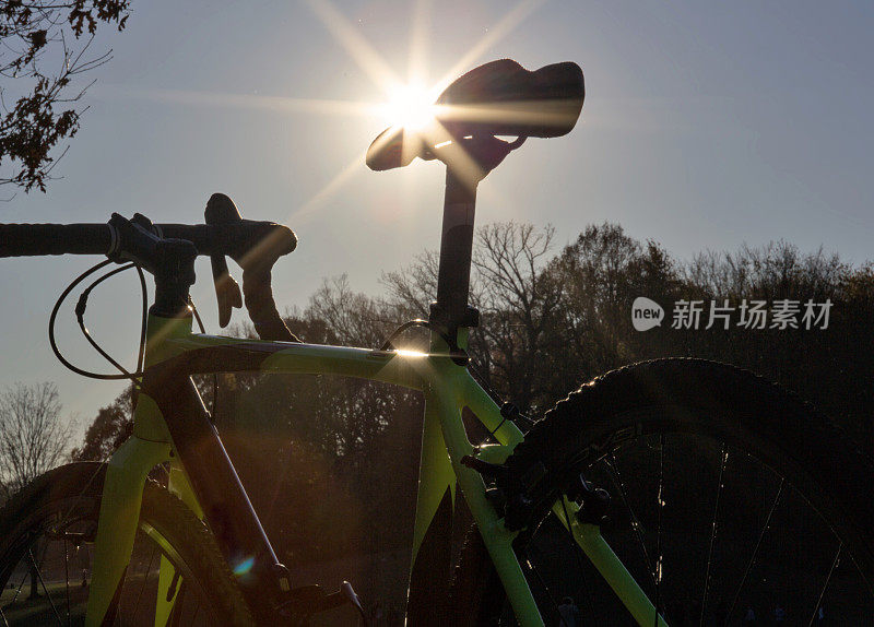 自行车车架后面，车座上有太阳光圈(车把、车轮、轮胎、铝制砾石自行车)。带有悬臂刹车的自行车(骑自行车、骑自行车、骑自行车)