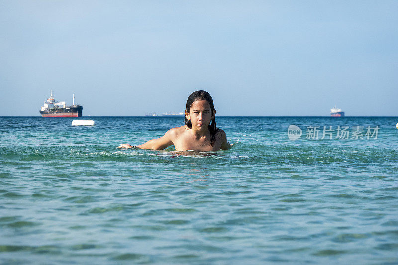 他用手在海里泼水。一个夏天的早晨。忒涅多斯岛。爱琴海北部，12岁的帅哥。长头发的