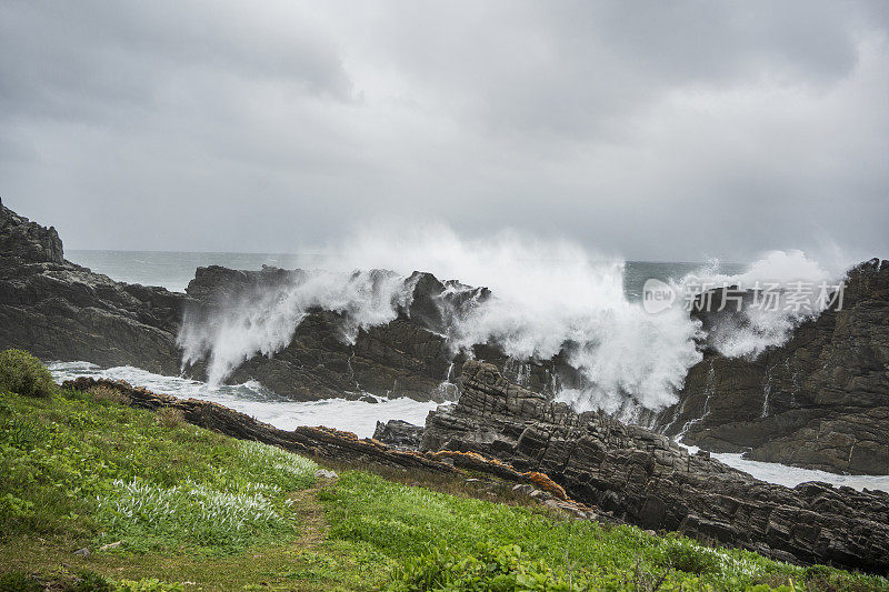 在一个阴天，海浪冲击着布满岩石的海岸线