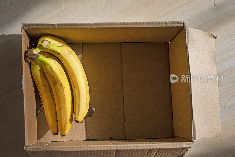 在阳光的照射下，装着香蕉的手工盒子。flatlay