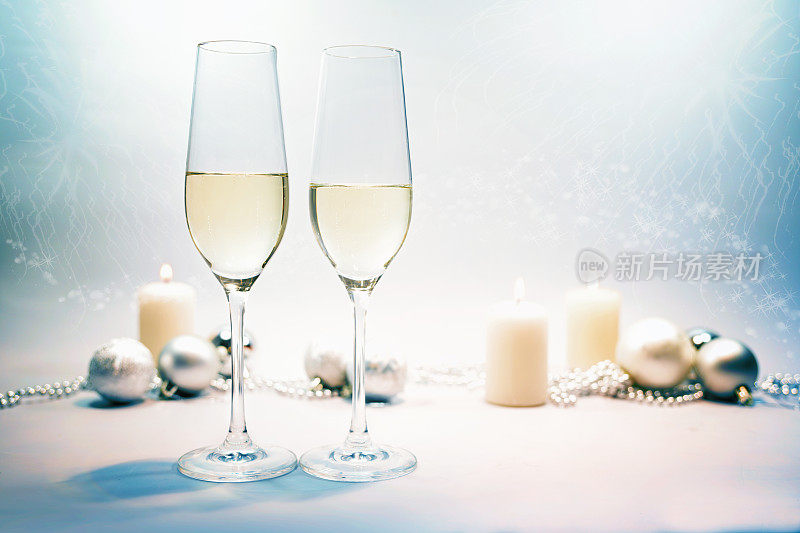 两个香槟酒杯，蜡烛和喜庆的圣诞装饰在蓝灰色的背景下配上淡淡的派对散景，为新年快乐，复制空间，选择焦点