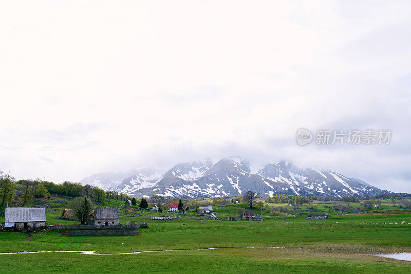 村庄坐落在雾蒙蒙的雪山脚下的绿色山谷里
