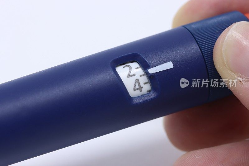 一名妇女拿着胰岛素笔，选择病人需要注射多少胰岛素