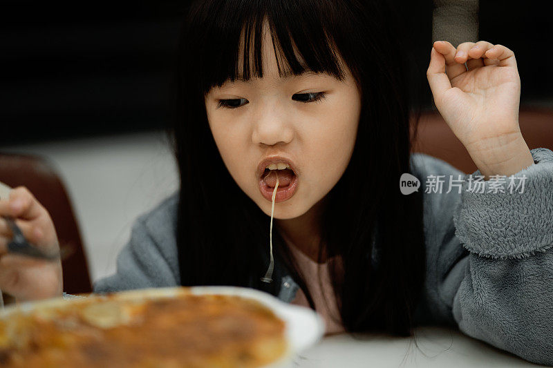 女孩们开心地吃起司面，一个亚洲女孩正在家里吃起司面。