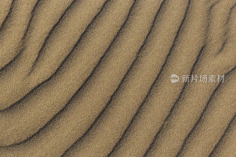 沙丘波浪和沙纹。海浪，沙丘。由于风的作用，沙子会改变形状，形成沙波纹和锯齿状的线条。有选择性的重点。副本的空间。
