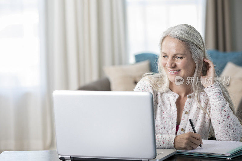 老妇人微笑着在网上与医疗保健专业人员从她的家交谈