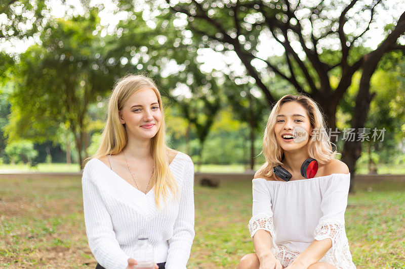 两个漂亮的年轻女人在公园里有说有笑。友谊快乐夏日野餐的生活方式