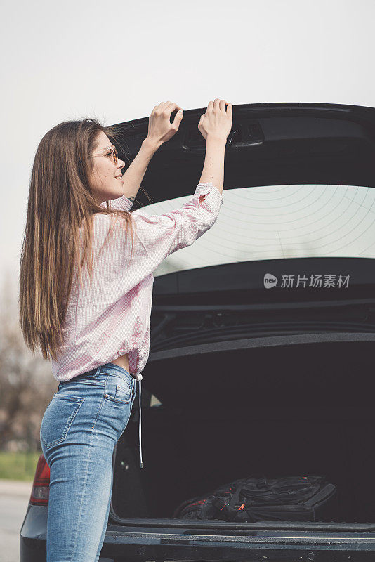 年轻的女人在关后备箱，装东西