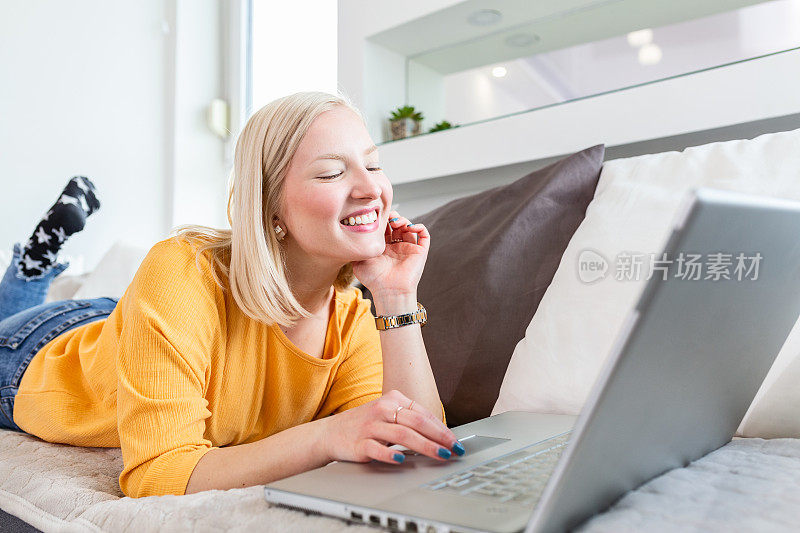 年轻的白化病妇女正在为她的企业做研究工作。微笑的女人坐在沙发上浏览网上购物网站。快乐的女孩在空闲时间在家上网。