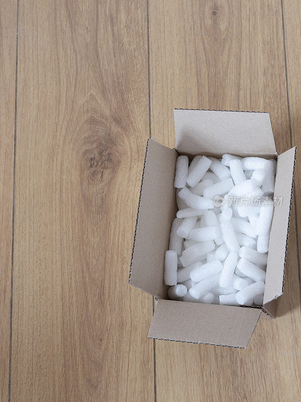 一个纸板箱与包装泡沫颗粒俯视图，在木地板上