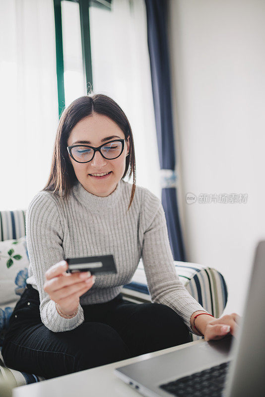 年轻女子在黑色星期五在家用信用卡购物