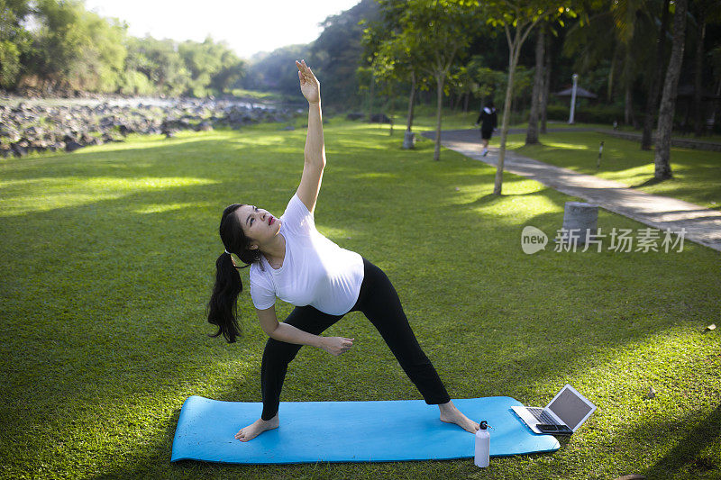 年轻的亚洲孕妇在公园里练习瑜伽