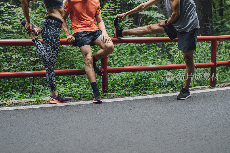 跑步伙伴:三个跑步者在自然中一起锻炼后聊天和伸展