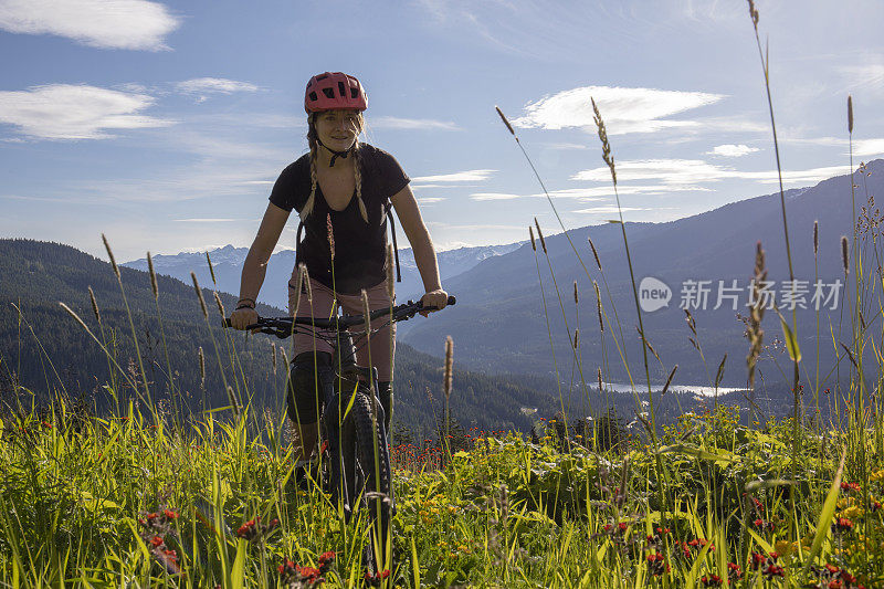 年轻女子骑山地车穿过山地草地