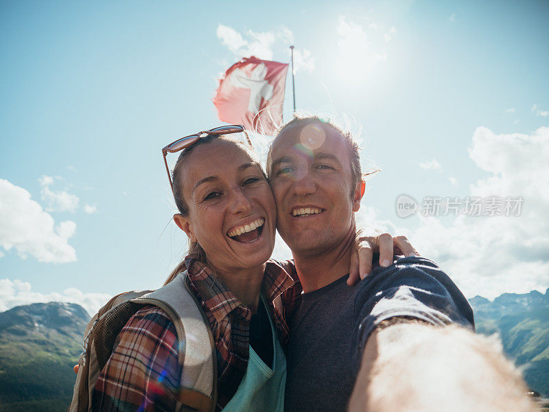 夫妇在山顶上举着瑞士国旗自拍