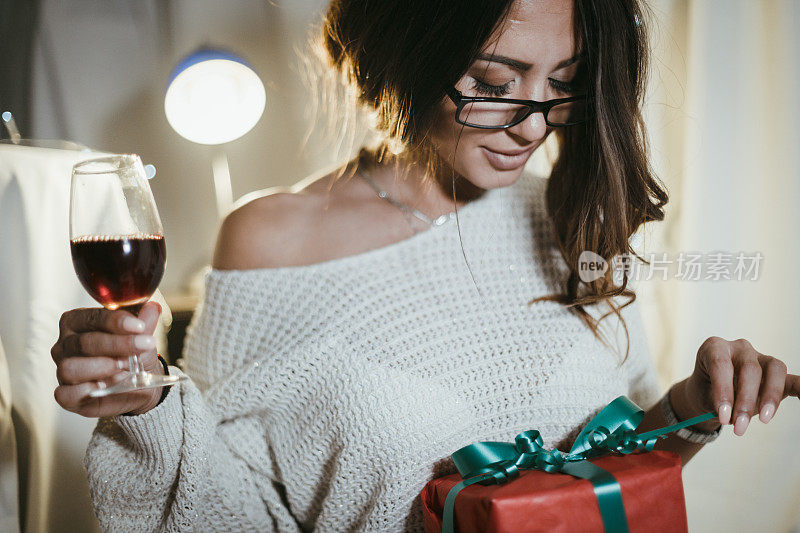 女人一边喝红酒一边拆圣诞礼物