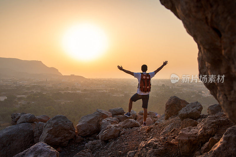 日落时分，一名男子在阿联酋沙漠山欣赏山顶景色