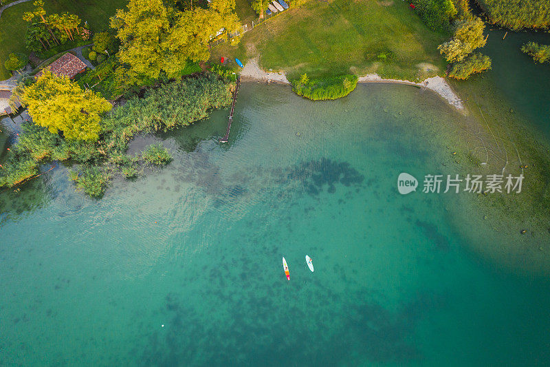 鸟瞰两个桨板在一个平静的湖在日落